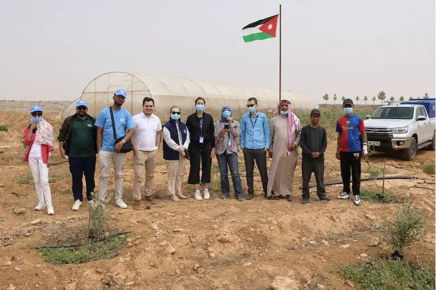 About-new-photo Agricultural team visiting a farm beneath the Jordanian flag.